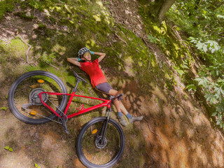 Cyclist teen rests in a forest after an adventurous bike ride