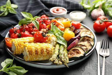 Delicious grilled vegetables served on grey textured table, closeup