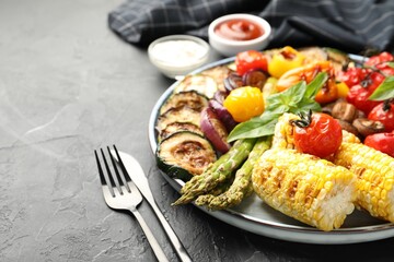 Delicious grilled vegetables served on grey textured table, closeup