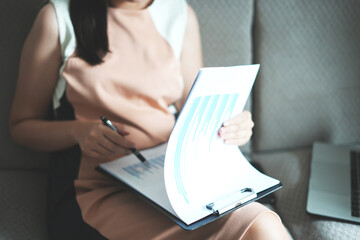 A young boss woman working at home and checking the paper documents of the company annual profits that the accountant submitted before she goes to work.