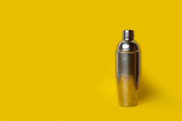 Una coctelera cromada sobre un fondo amarillo aislado. ista de rente y de cerca. Copy space