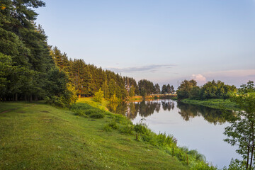 A river with a green bank and trees in the background