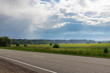 Lush green fields stretch under a dynamic sky, with clouds shifting as a gentle breeze sweeps...