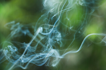 Smoke from incense stick on green blurred background