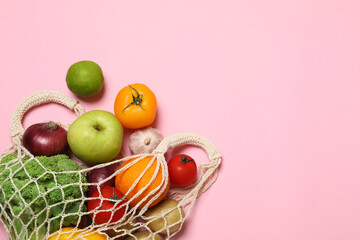 Delivery of vegetarian products. String bag with different vegetables and fruits on pink background, top view. Space for text