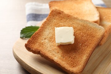 Delicious toasted bread slices with butter on table, closeup