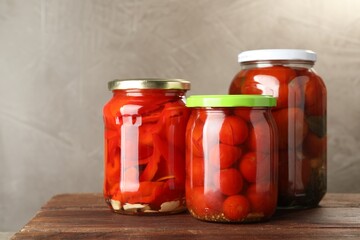 Different pickled vegetables in jars on wooden table