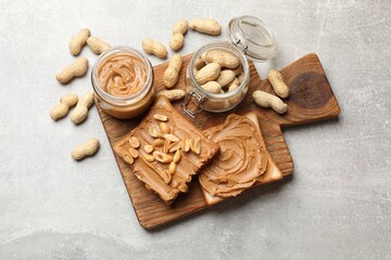 Tasty sandwiches with peanut butter and nuts on grey textured table, flat lay
