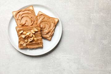 Tasty sandwiches with peanut butter and nuts on grey textured table, top view. Space for text