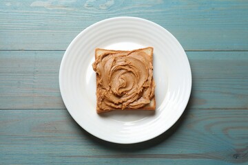 Tasty sandwich with peanut butter on light blue wooden table, top view
