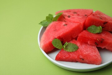 Pieces of tasty watermelon and mint on green table, closeup. Space for text