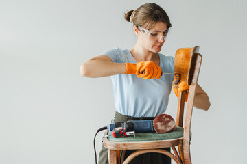 Woman concentrating on repairing old wooden chair using screwdriver