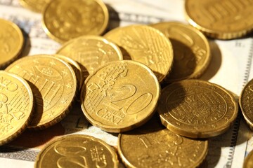 Many euro coins on dollar banknotes, closeup