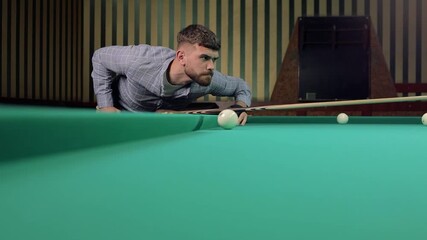 Man plays american or russian billiards in a pub billiard club or bar with special glove, hit the pyramid, taking a shot with his cue stick. The balls on the green felt table

