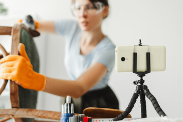 Carpenter restoring furniture while recording diy video blog using smartphone