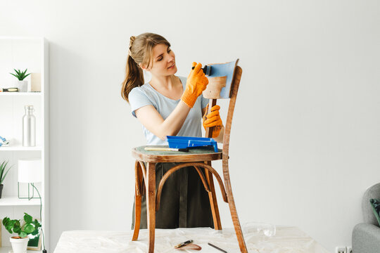 Woman restoring old furniture applying protective coating using brush