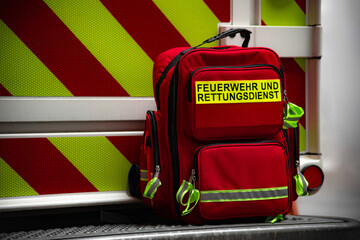Rettungsrucksack mit der Aufschrift "FEUERWEHR UND RETTUNGSDIENST" eines Sanit&auml;ters vor einem Rettungswagen im Einsatz