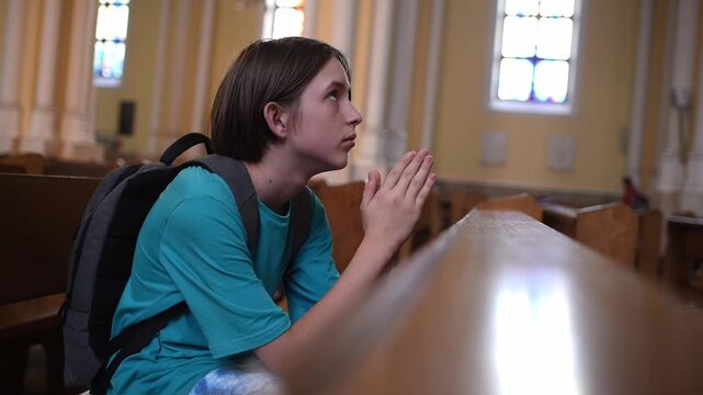 11 year old boy or teenager prays in the temple. Child, Catholic communicates with God in the church, cathedral.	
