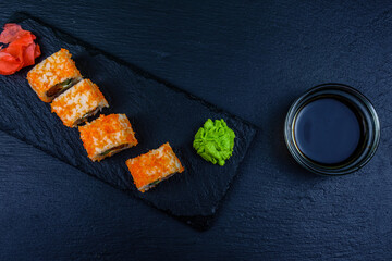 Sushi roll philadelphia with salmon, rice, cheese, cucumber, avocado and caviar on a slate board. Japanese food. Top view