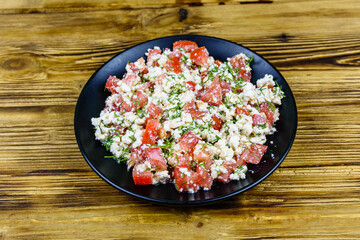 Salad with tomatoes, cottage cheese, dill and olive oil on a wooden table