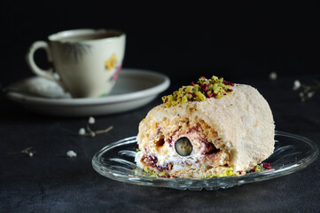 Delicious meringue roll with cream and jam, on a saucer close-up. Selective focus, natural light