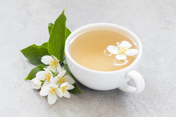 Green Tea with jasmine in a white cup. Light gray background. Close up	