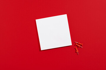 Empty white paper sheet for notices with red stationery pins on a red background, copy space. Back to school concept