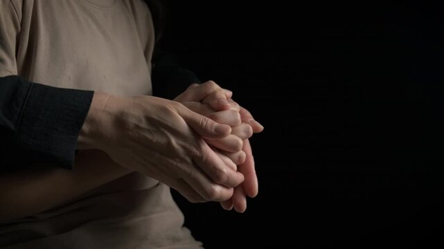 Mom hold teen hand on black. A mother try to hold depressed teen on her hands in the black background.