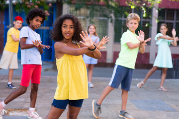 Fototapeta premium Positive african-american girl performing street dance with her friends outdoors.