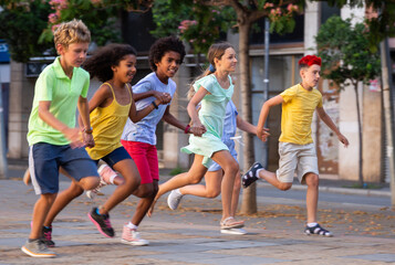 Obraz premium Group of smiling kids holding each other hands while running through city streets together.