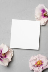 Square paper card mockup with fresh flowers on grey backgroound, copy space for card design