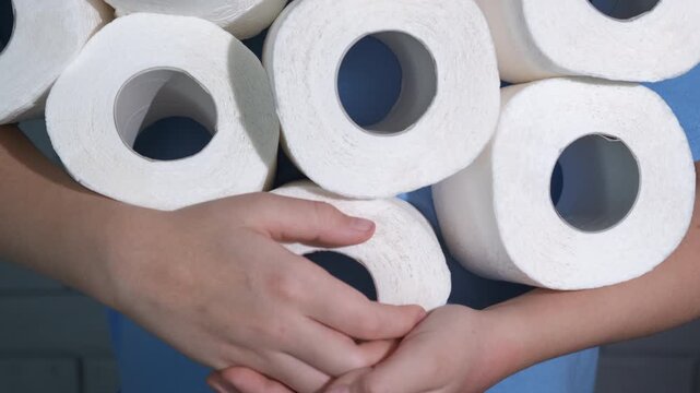 Girl stock up toilet paper. A view of girl hands stock up the toilet paper in the bathroom during crisis time.