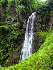 Naklejka premium Waterfall the Giant or Velikan in Abkhazia, great spring in mountain in summer. Concept of forest, water, nature, landscape, travel