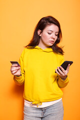 Female customer using a smartphone app to shop online with a credit card. Portrait of contemporary woman uses her phone to make a purchase using money from a bank. Shopaholic grown-up.