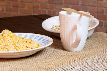 Homemade peanut brittle in an old plate next to a mug on top of a rustic tablecloth