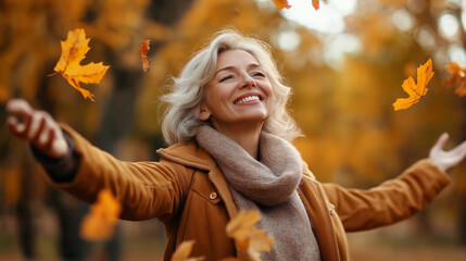 An elderly woman enjoying a moment in an autumn park with falling leaves. The fall of life, like the fall of the year, should be gratefully accepted. The concept of active age