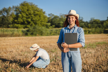 Portrait of young woman farmer stand in the field with clipboard