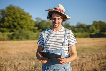 Portrait of adult man farmer stand in the field with clipboard