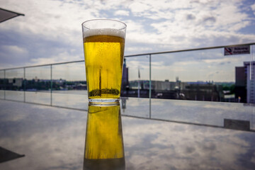 A full glass of beer is on a table outside