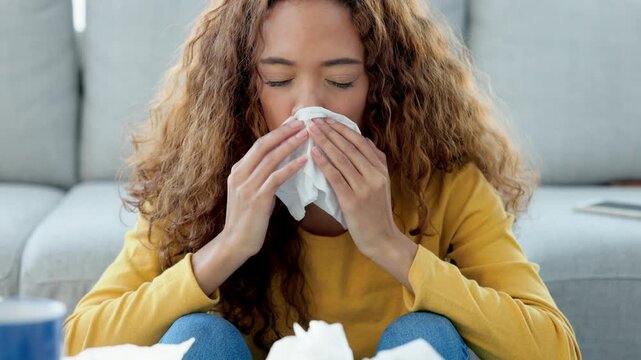 Sick young woman with flu or an allergy sneezing in a tissue and blowing nose. Ill girl caught a bad cold showing symptoms of covid, or suffering from a virus disease. Person with a sinus infection