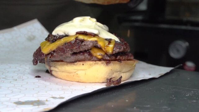 chef making doble smashed burger with bacon jam and mayo