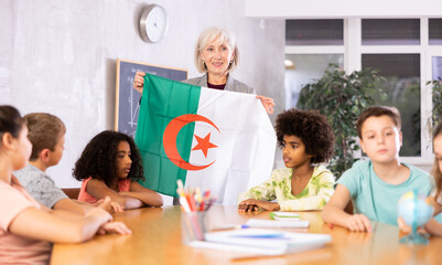 in geography lesson, pupils carefully listen to woman teacher who talks about Argentina