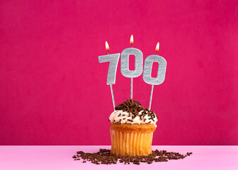 Birthday celebration with candle number 700 - Chocolate cupcake on pink background
