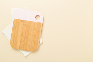 Cutting board with napkin on color background, top view
