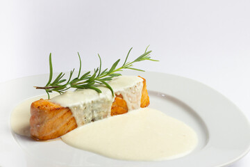 Salmon steak with sauce and rosemary on a white plate