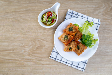 Fried Bread with Minced Pork Spread in white plate on the wooden table, traditional snacks and appetizers in Thailand