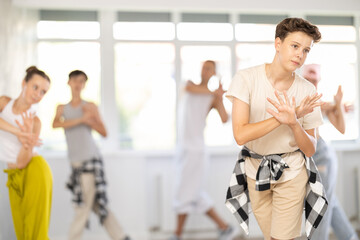 Teen guy together with group of teen friends, learn to dance hip hop in choreo hall. Team of...