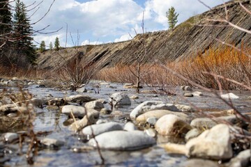 A Stream Running Through A Dry Grass Covered Field.