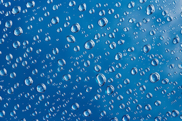 Water drops on blue background. Rain drops on glossy window glass.