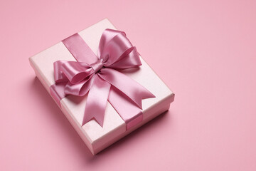 Beautiful gift box with color bow on pink background. Space for text